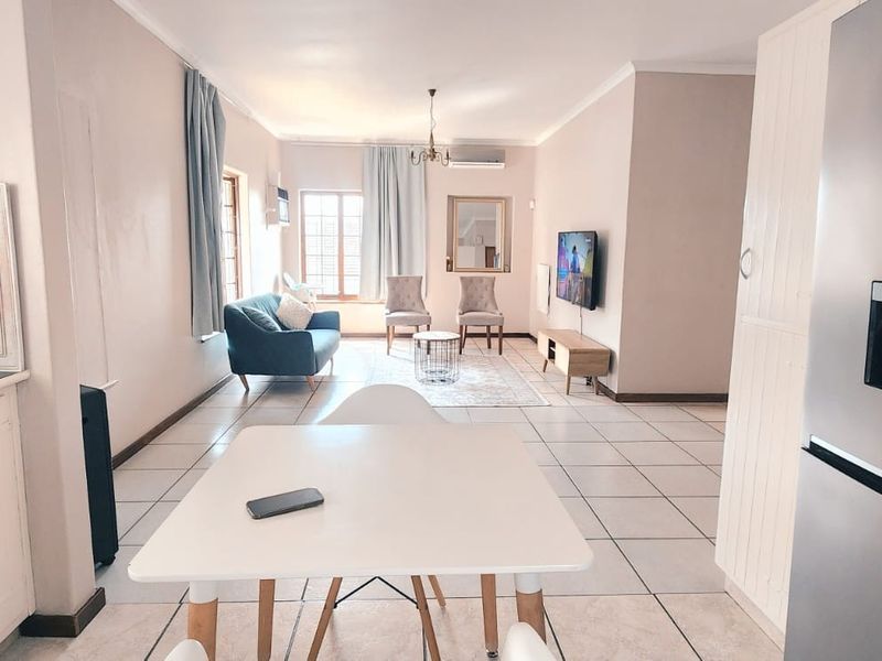 An open-plan living and kitchen area featuring tiled flooring, built-in cabinetry, and an air conditioning unit, creating a functional and connected living space.