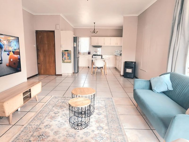 Open-plan living and kitchen area featuring tiled flooring, neutral wall tones, and a functional kitchen layout with built-in cabinetry.