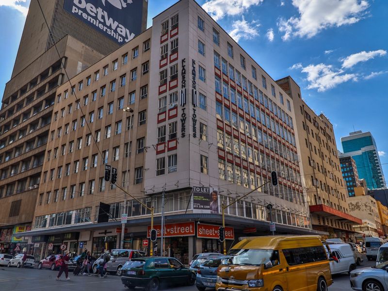 A multi-story commercial building located on a busy street corner, featuring ground-level retail space and prominent signage.