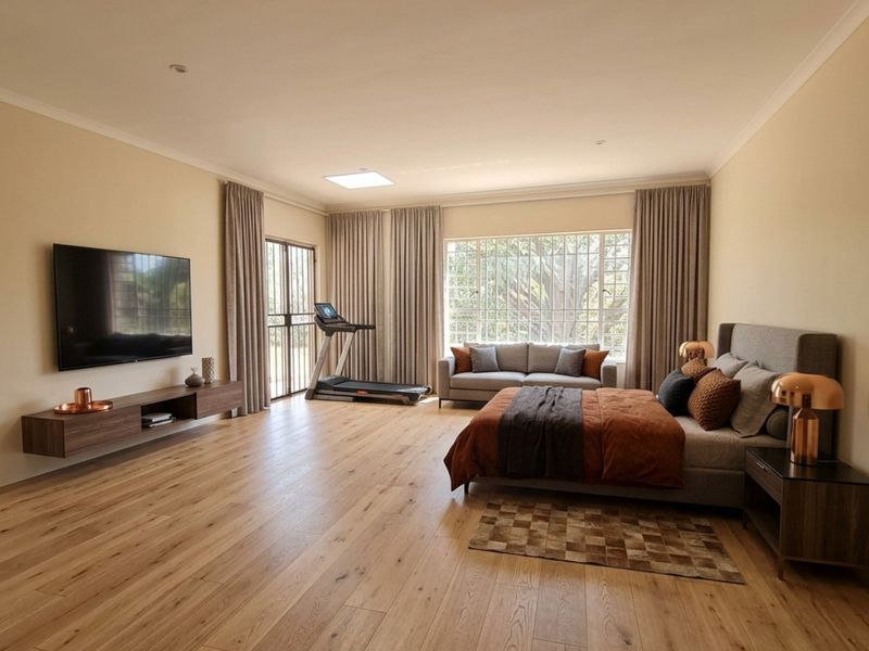 Spacious primary bedroom featuring light timber flooring, recessed lighting, a floating media console, and large windows providing ample natural light.