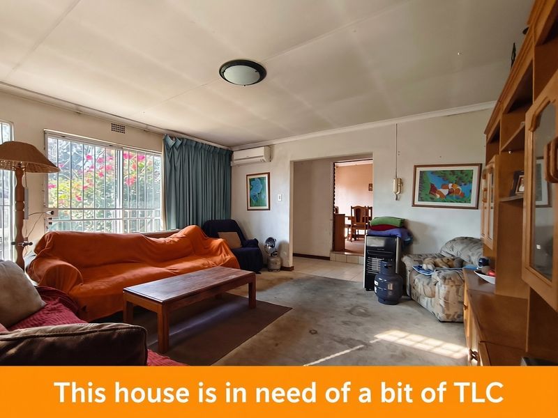 Spacious living room featuring security bars on windows and a wall-mounted air conditioning unit, offering a functional layout in need of cosmetic updates.