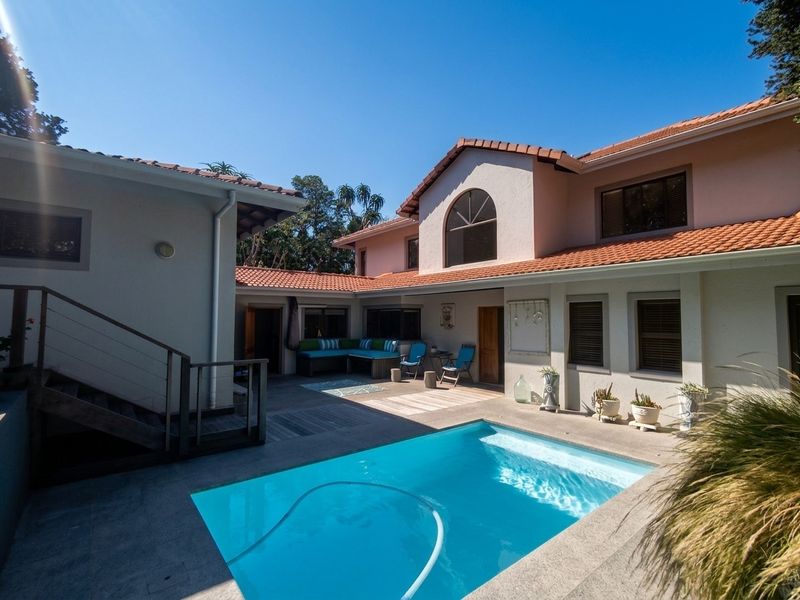 A well-maintained rear courtyard featuring a swimming pool, paved patio area, and access to the main house via an external staircase.
