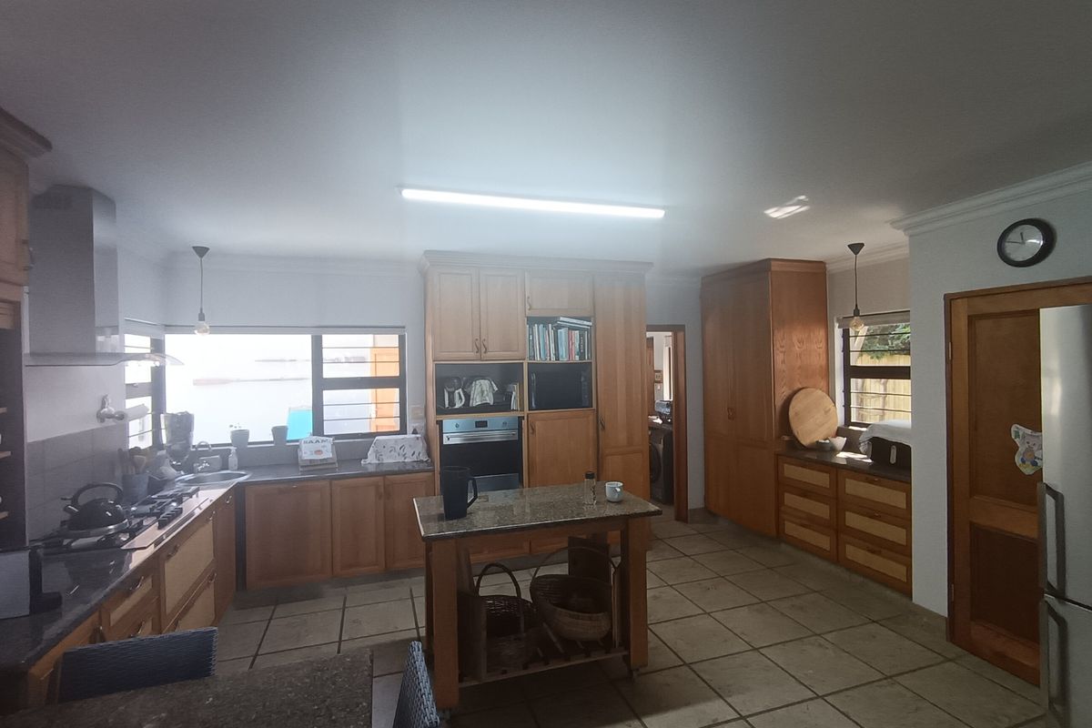 Spacious kitchen featuring extensive wooden cabinetry, granite countertops, a central island, and built-in appliances, offering a functional layout with ample storage space.