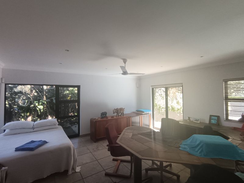 Spacious bedroom featuring tiled flooring, ceiling fan, and large sliding glass doors providing natural light and garden access.