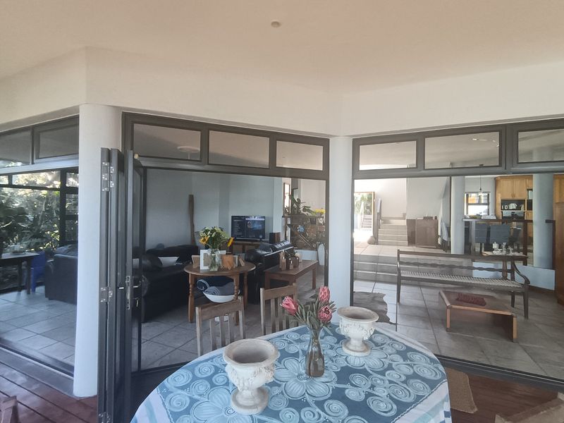 Covered patio area featuring large folding glass doors that provide seamless access to the open-plan living and dining spaces.
