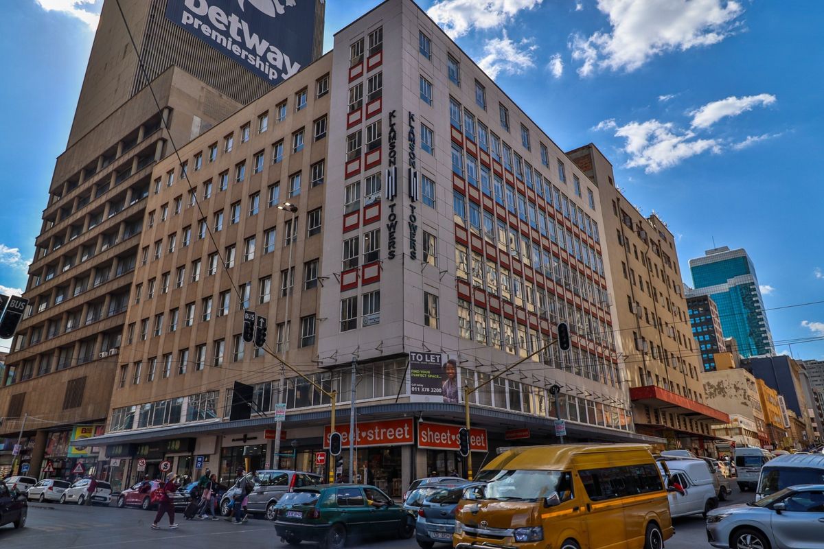 A multi-story commercial building located on a busy street corner, featuring ground-level retail space and prominent signage.
