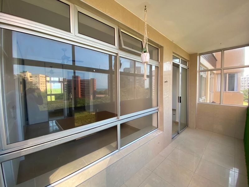 A clean, tiled balcony featuring modern aluminium-framed windows and a sliding glass door, offering a bright and versatile outdoor space.