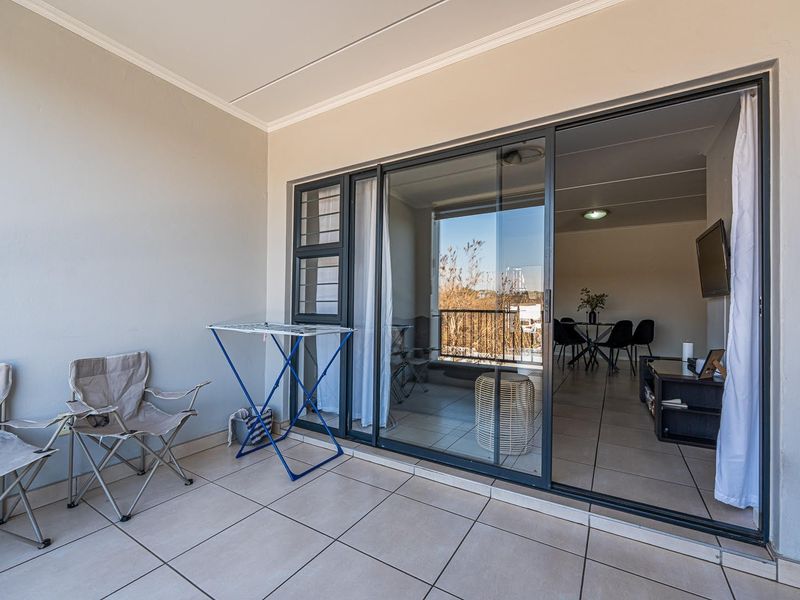A covered balcony featuring tiled flooring and large sliding glass doors that provide seamless access to the interior living area.