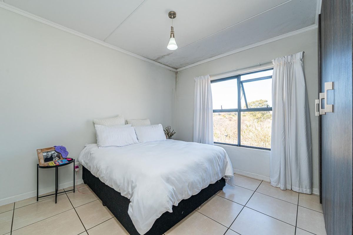 A bedroom featuring tiled flooring, a built-in wardrobe, and a window with natural light. Note visible ceiling damage requiring repair.