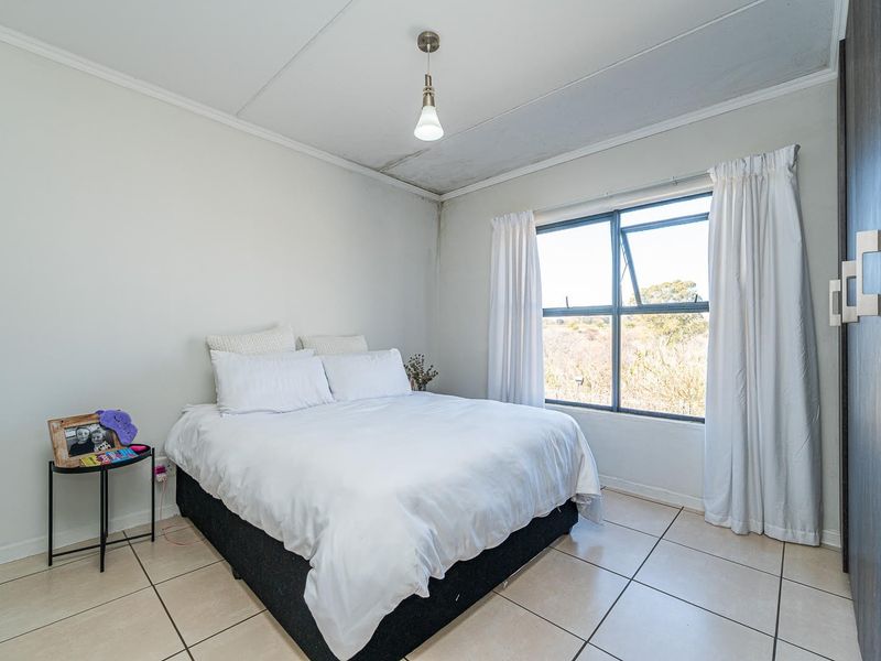 A bedroom featuring tiled flooring, a built-in wardrobe, and a window with natural light. Note visible ceiling damage requiring repair.