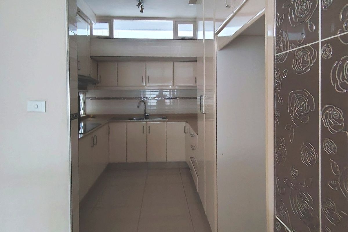 A functional kitchen featuring neutral built-in cabinetry, tiled flooring, and a tiled backsplash, offering a clean and practical workspace.