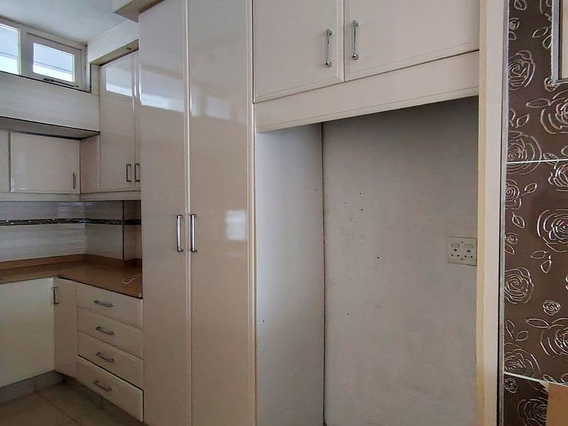 A functional kitchen featuring built-in cabinetry, laminate countertops, and a dedicated refrigerator alcove, offering a clean canvas for potential updates.