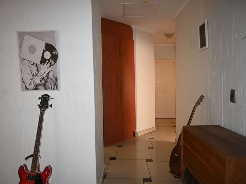 A functional hallway featuring tiled flooring and a built-in wooden cupboard, providing access to other areas of the townhouse.