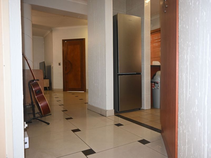 A tiled hallway area featuring a structural column and access to adjacent living spaces and a kitchen area.