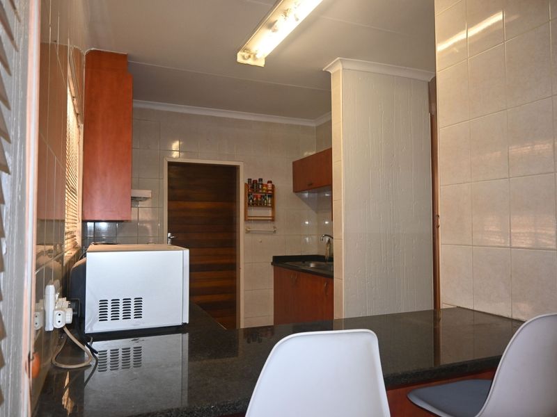 A functional kitchen featuring granite countertops, tiled backsplash, and built-in wooden cabinetry with a breakfast bar area.