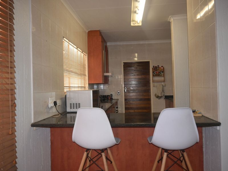 A functional kitchen featuring a granite breakfast bar, tiled walls, and built-in cabinetry, offering a practical layout for daily use.