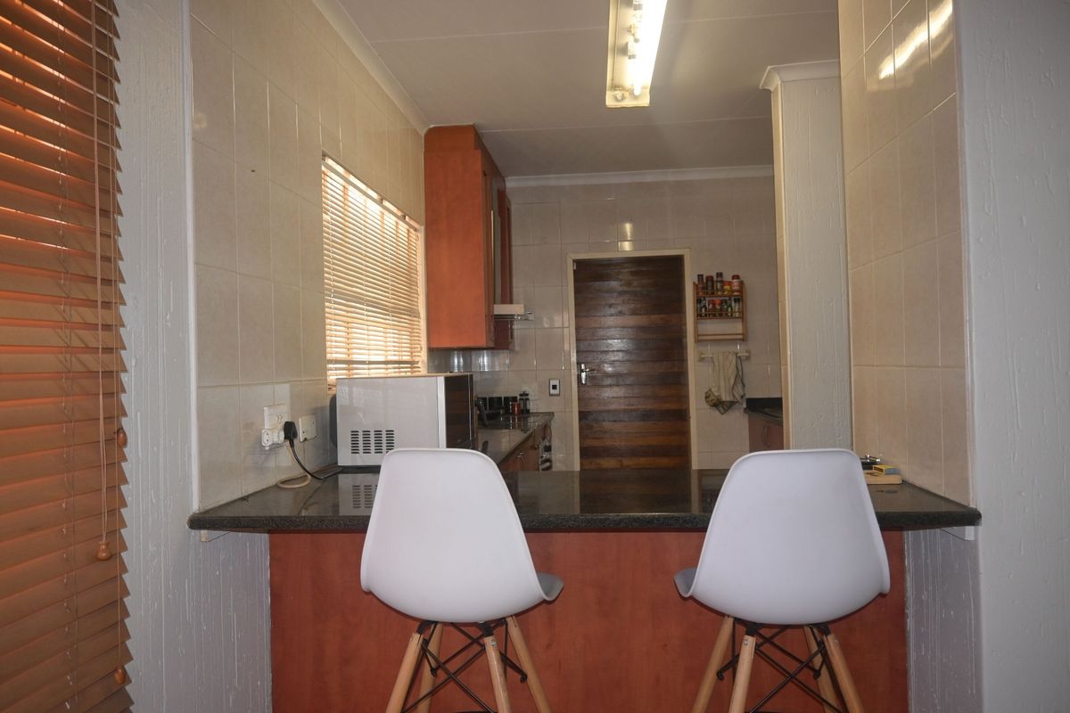 A functional kitchen featuring a granite breakfast bar, tiled walls, and built-in cabinetry, offering a practical layout for daily use.