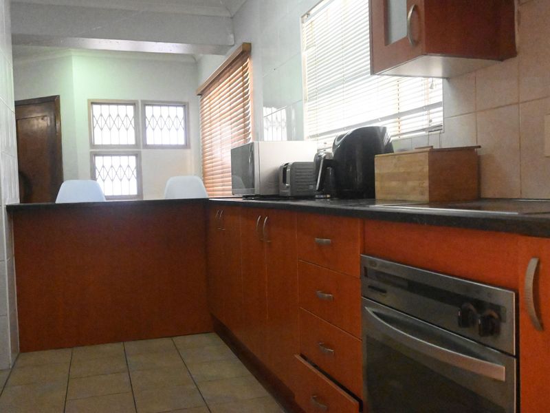 A functional kitchen featuring built-in cabinetry, laminate countertops, and a built-in oven, with tiled flooring and venetian blinds.