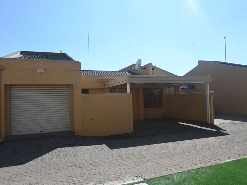 Front exterior view of a townhouse featuring a single garage, a covered carport, and a paved driveway.