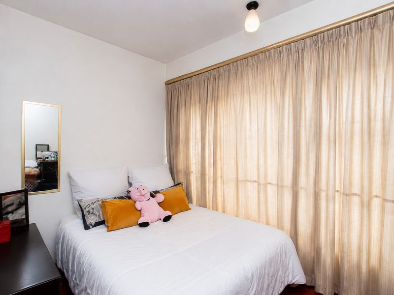A cozy bedroom featuring neutral wall finishes, a ceiling light fixture, and full-length curtains covering the window area.