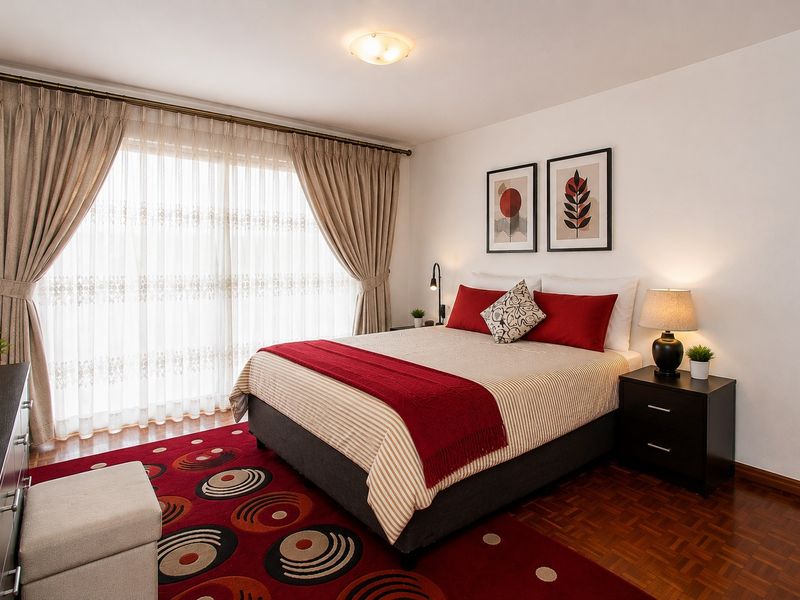 A well-maintained bedroom featuring warm parquet flooring, a large sliding glass door with curtains, and a central ceiling light fixture.