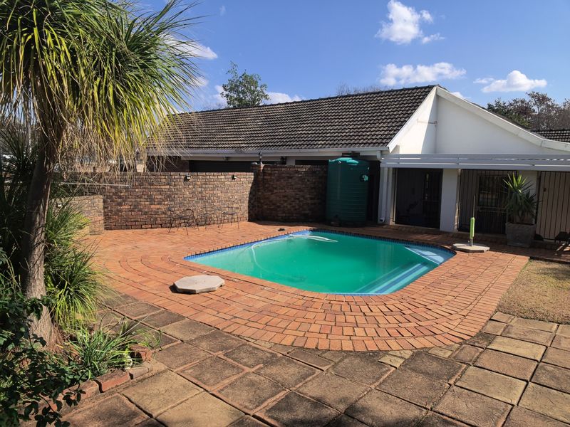 Outdoor pool area featuring a swimming pool, brick paving, and a brick boundary wall with an integrated water storage tank.