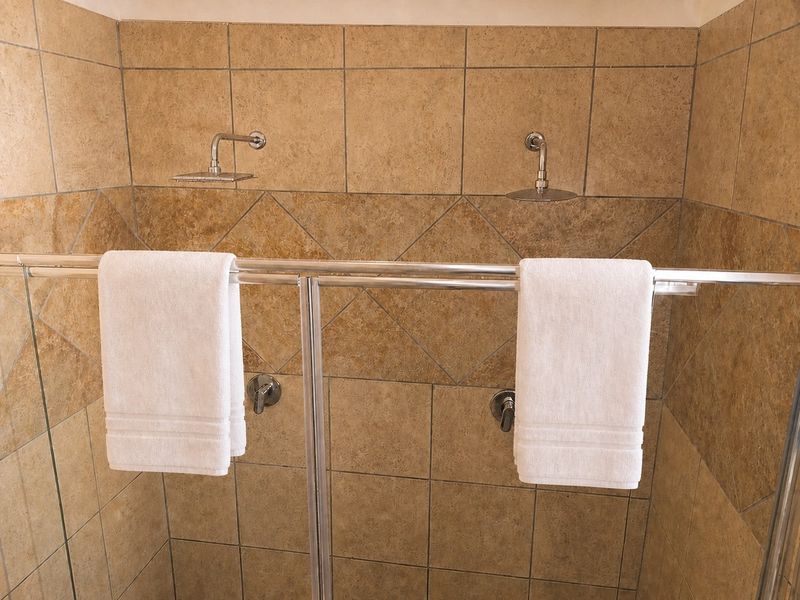 A tiled shower enclosure featuring dual shower heads and a glass screen, providing a functional and spacious bathing area.