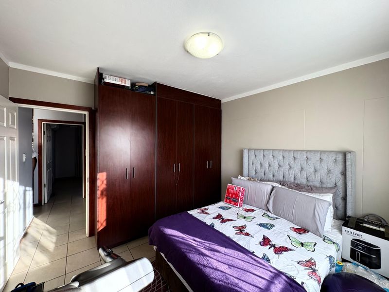 A bedroom featuring dark wood built-in cupboards, tiled flooring, and a central ceiling light fixture.