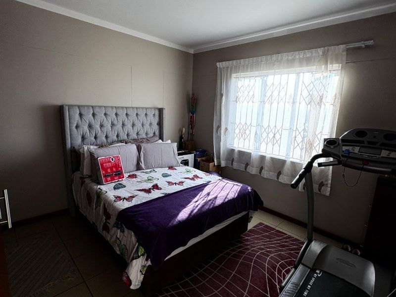 A bedroom featuring tiled flooring, a ceiling light fixture, and a window fitted with a security gate.