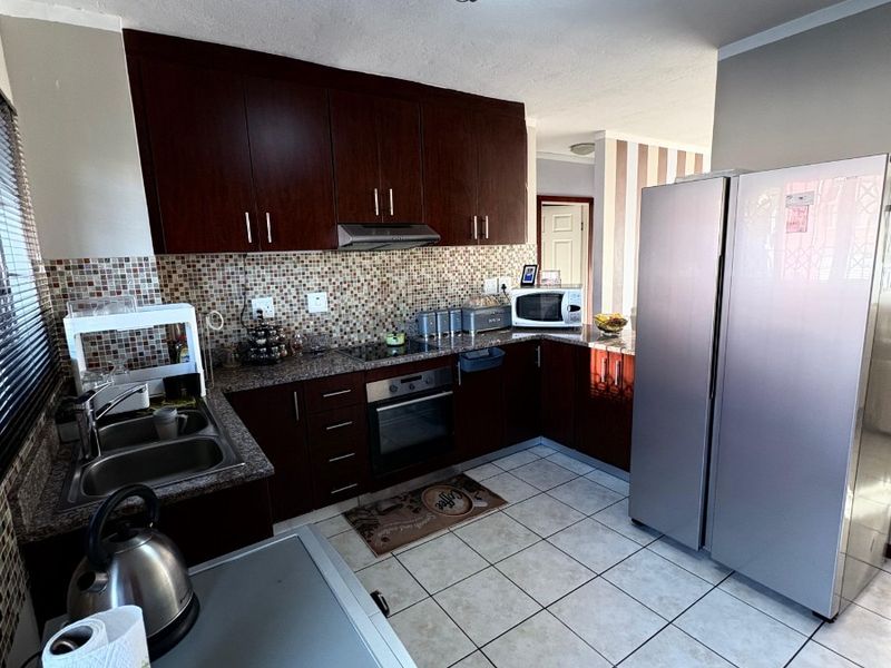Functional kitchen featuring dark wood cabinetry, granite countertops, mosaic tile backsplash, and built-in oven with extractor fan.