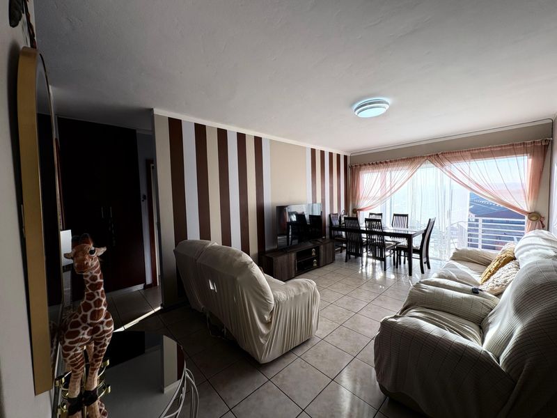Open-plan living and dining area featuring tiled flooring and neutral wall finishes, offering a functional layout with natural light.