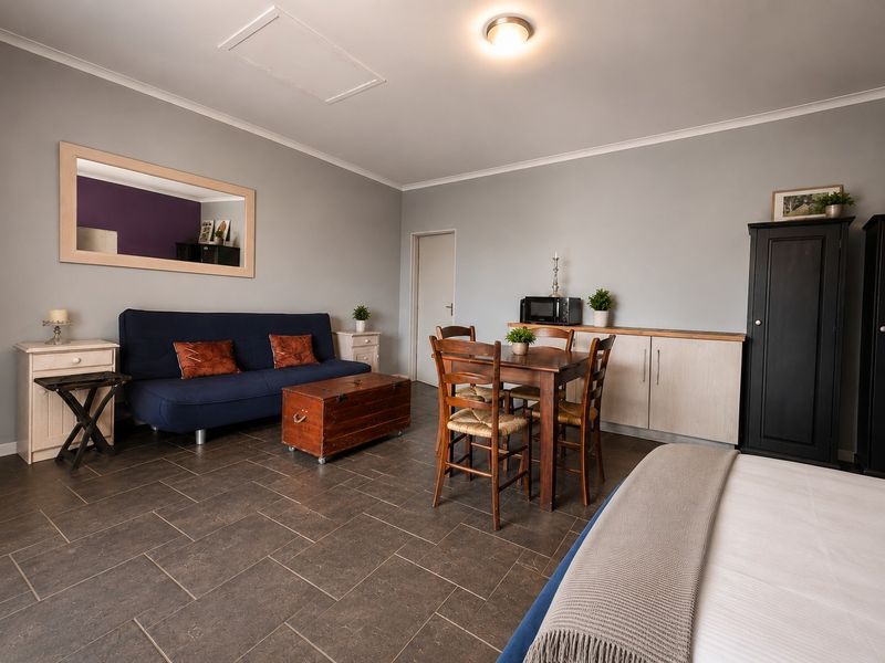 An open-plan living and dining area featuring dark tiled flooring, neutral wall tones, and built-in storage cabinetry.