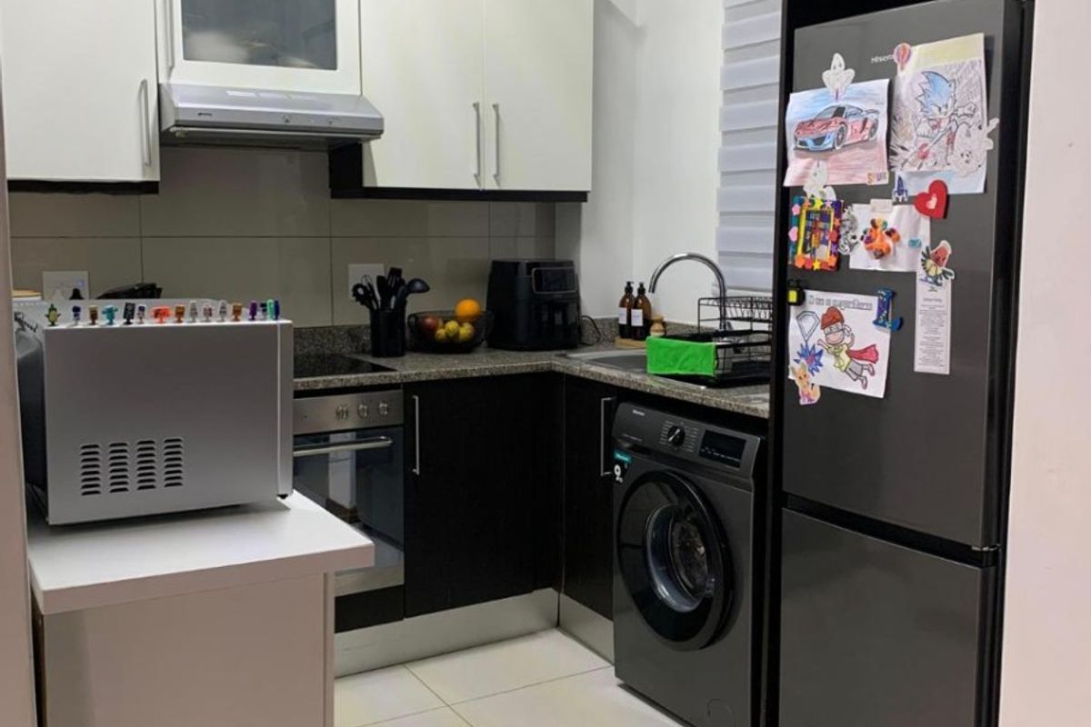 Compact modern kitchen featuring two-tone cabinetry, granite countertops, built-in oven, extractor fan, and integrated laundry facilities with tiled flooring.