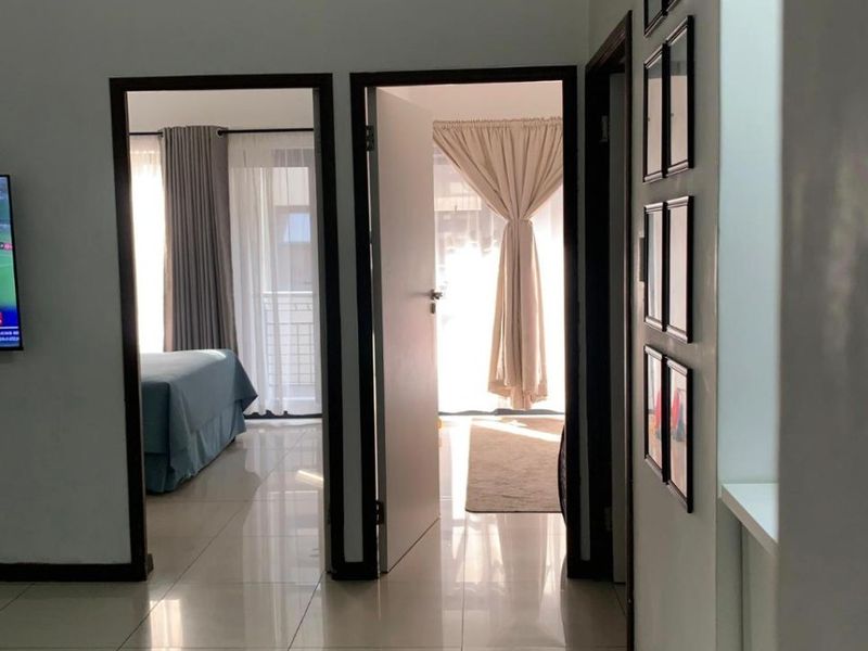 A bright hallway with polished tile flooring, providing access to adjacent bedrooms and living areas.