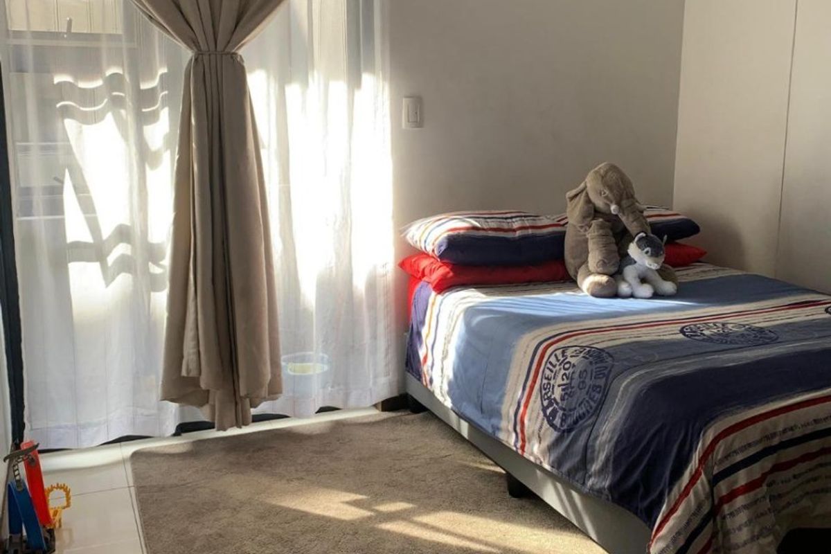 A bedroom featuring tiled flooring and a sliding glass door that provides natural light.