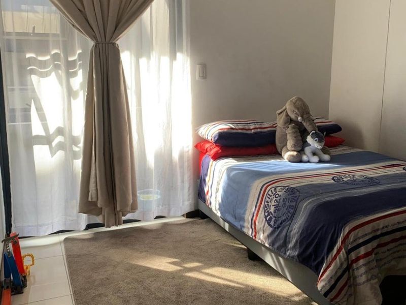 A bedroom featuring tiled flooring and a sliding glass door that provides natural light.