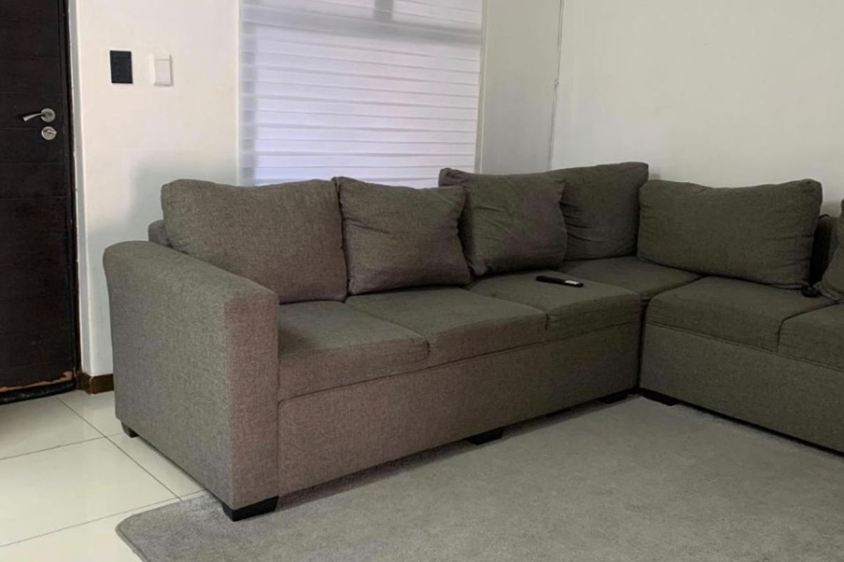 A living room featuring tiled flooring, a wall-mounted split-system air conditioner, and a window fitted with a roller blind.