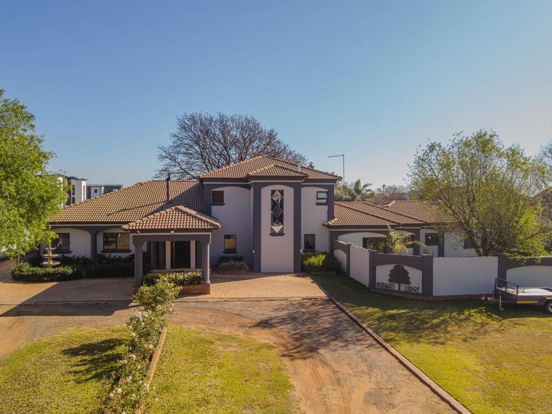 Aerial view of a large residential property featuring a tiled roof, paved driveway, and a prominent covered entrance.