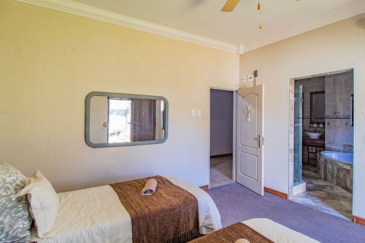 A bedroom featuring carpeted flooring, crown molding, a ceiling fan, and direct access to an en-suite bathroom with a bathtub.