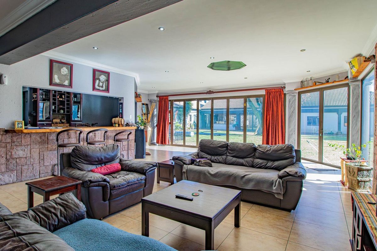 Spacious living room featuring a built-in bar with stone cladding, tiled flooring, and large sliding glass doors providing access to the rear garden.
