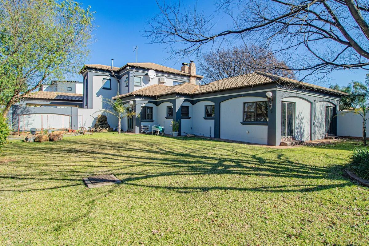 A view of the rear elevation of the house featuring a large lawn, tiled roof, and sliding door access to the garden.