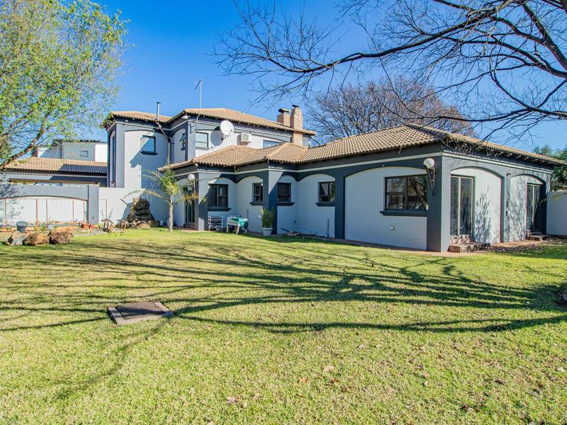 A view of the rear elevation of the house featuring a large lawn, tiled roof, and sliding door access to the garden.