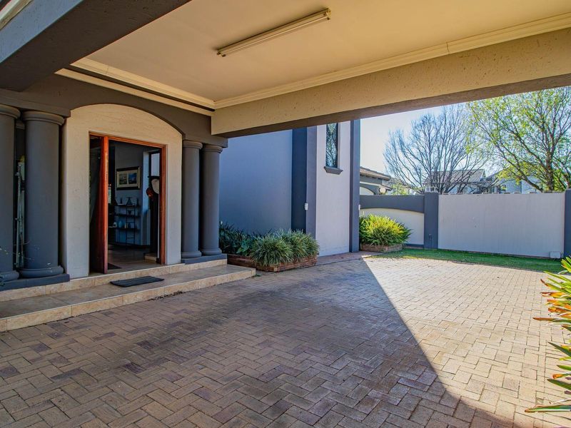A well-maintained front entrance featuring a covered porch, paved driveway, and architectural columns, providing a welcoming and secure access point to the home.