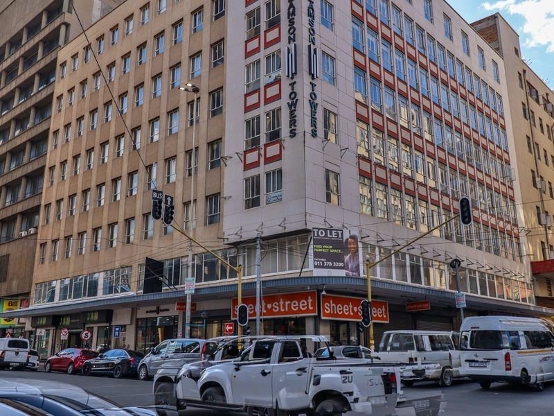 Exterior view of Samson Towers, a multi-story commercial building featuring ground-floor retail spaces and prominent street-level signage in a busy urban setting.