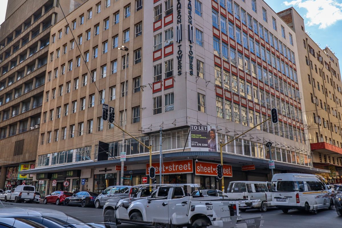 Exterior view of Samson Towers, a multi-story commercial building featuring ground-floor retail spaces and prominent street-level signage in a busy urban setting.