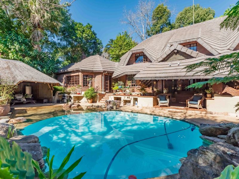 A beautifully landscaped backyard featuring a circular swimming pool, a charming thatched gazebo, and a brick-clad home with a spacious covered patio area.