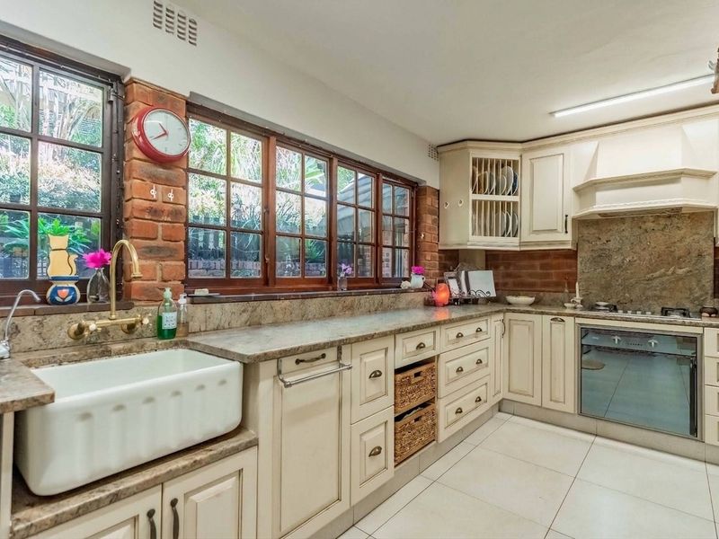 A charming kitchen featuring farmhouse sink, stone countertops, exposed brick accents, and built-in appliances, offering a warm and functional culinary space.