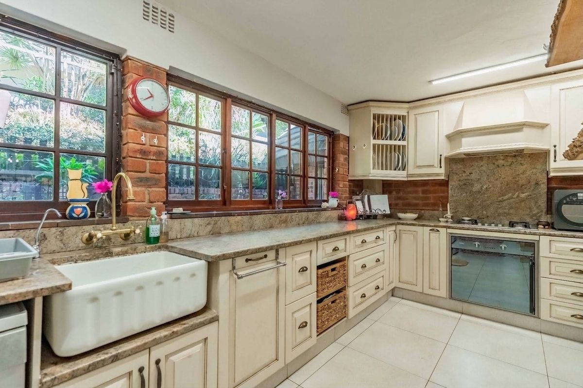 A charming kitchen featuring farmhouse sink, stone countertops, exposed brick accents, and built-in appliances, offering a warm and functional culinary space.