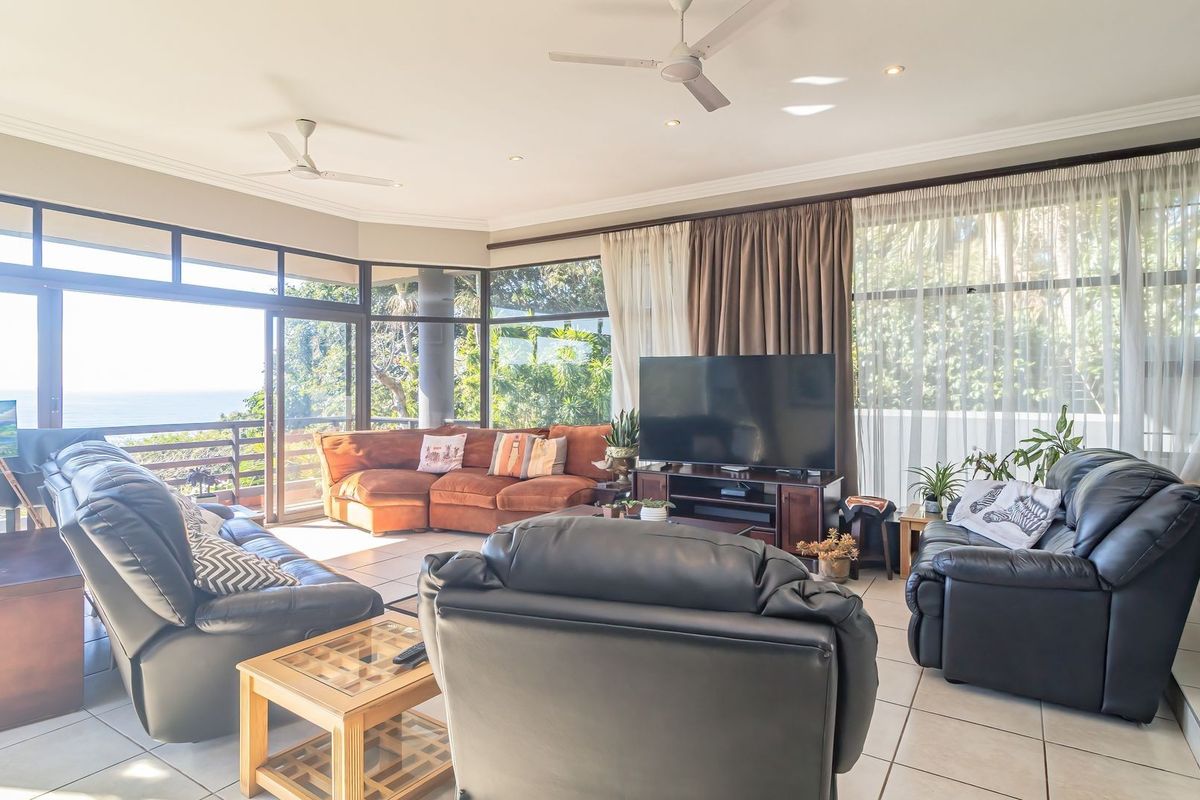 Spacious living room featuring large glass sliding doors that provide ample natural light and views, complemented by tiled flooring and ceiling fans.