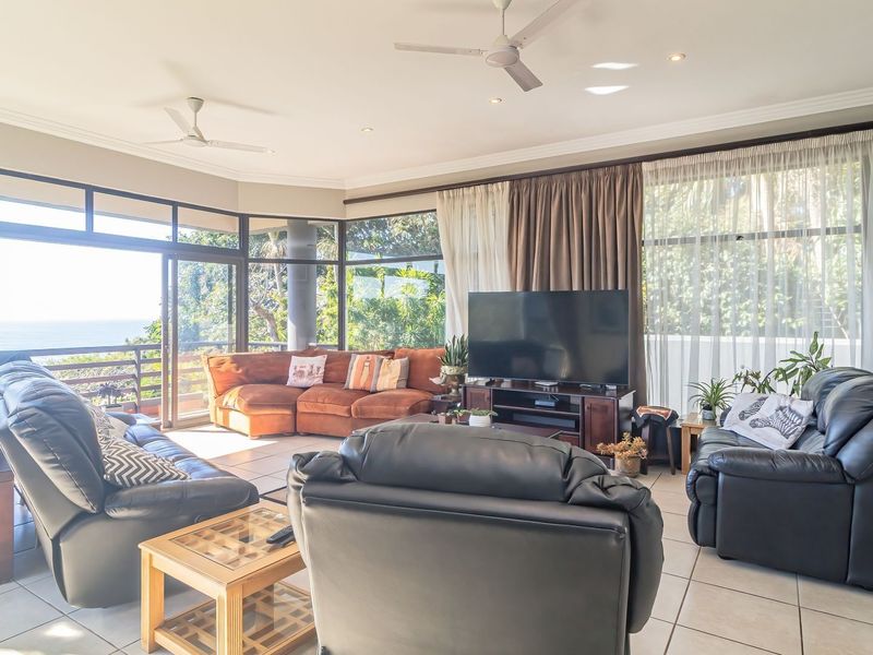 Spacious living room featuring large glass sliding doors that provide ample natural light and views, complemented by tiled flooring and ceiling fans.
